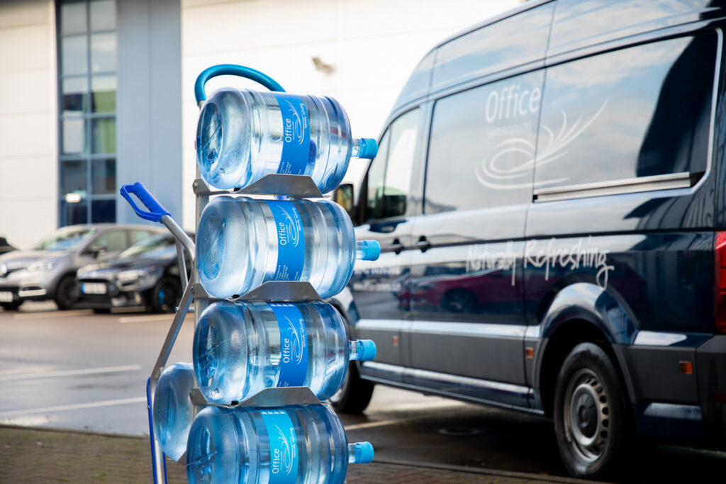 Water cooler bottles on a delivery rack placed next to a delivery van