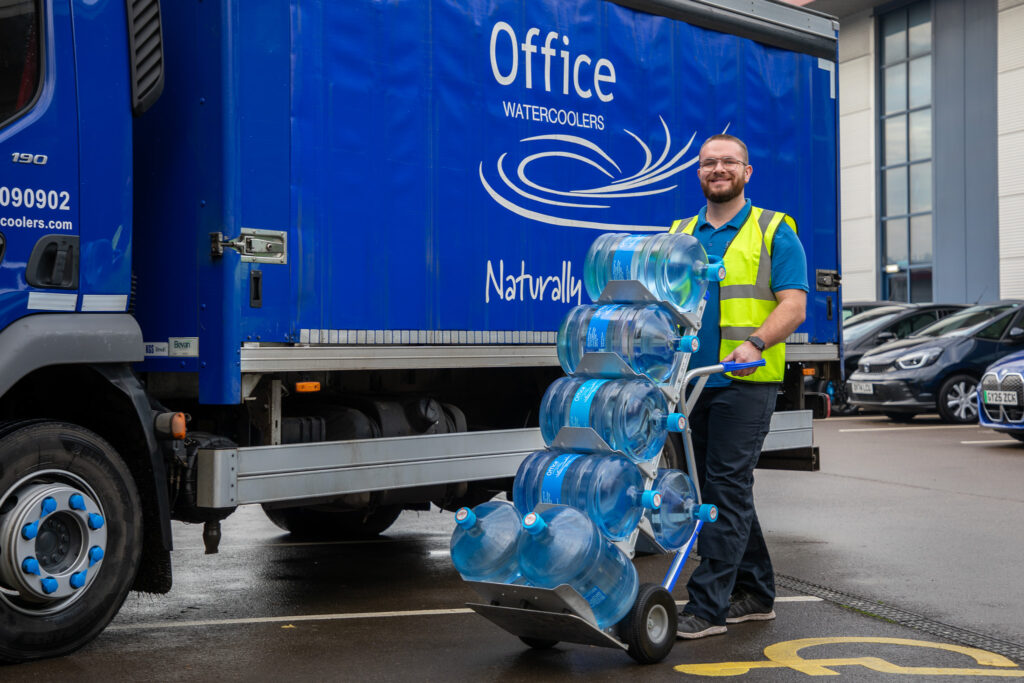 Engineer delivering water bottles whilst walking in front of a delivery van